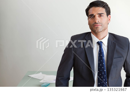 Mid adult man in suit standing at office desk reviewing papers and checking smartphone, copy space 135321987