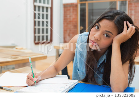 Asian female student writing in notebook at study table with blue binder and pen, copy space Asian female student writing in notebook at study table with blue binder and pen, copy space 135322008
