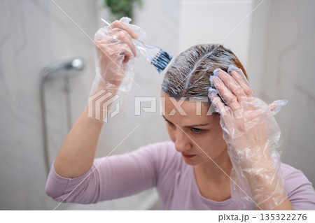 Woman dyeing her hair at home in the bathroom 135322276
