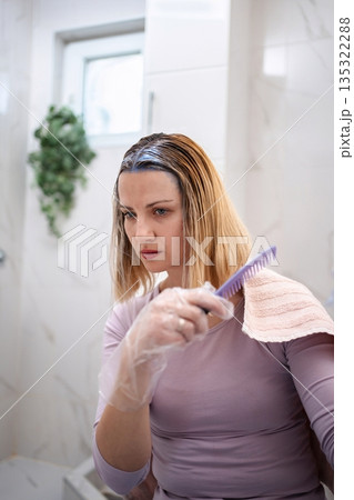 Young Woman Dyeing Hair at Home in Bathroom 135322288