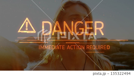 Standing shirtless man on rocky coast at sunset, showing overlay DANGER IMMEDIATE ACTION REQUIRED 135322494