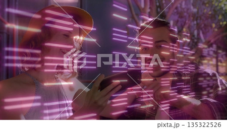 Leaning woman in straw hat and plaid-shirt man smiling while viewing smartphone at neon-lit lounge 135322526
