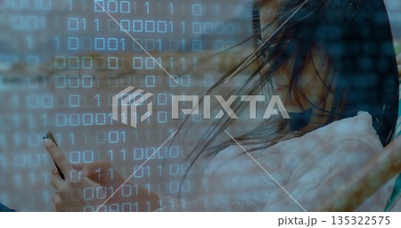 Asian woman wearing knit sweater holding smartphone under binary code overlay in car cabin headrest 135322575