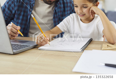 Father and happy daughter draw together with pencils on paper notebook at home Father and happy daughter draw together with pencils on paper notebook at home 135322658