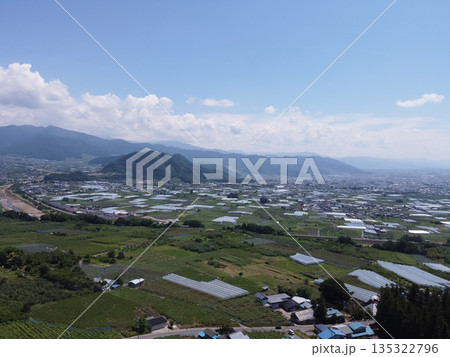 長野の中野市の農園と夏の青空 雄大な山並みと果樹園の風景(ドローン空撮) 長野の中野市の農園と夏の青空 雄大な山並みと果樹園の風景(ドローン空撮) 135322796