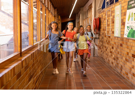 Diverse group of children running in a school hallway Diverse group of children running in a school hallway 135322864