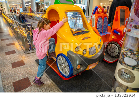 Little girl riding coin operated toy car attraction in shopping mall kids area. Childhood entertainment moment, family leisure activity and everyday fun experience in real life commercial environment Little girl riding coin operated toy car attraction in shopping mall kids area. Childhood entertainment moment, family leisure activity and everyday fun experience in real life commercial environment 135322914