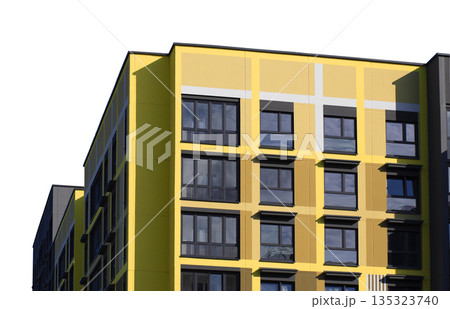 Modern apartment building with a bold yellow facade and dark framed windows, isolated on white Modern apartment building with a bold yellow facade and dark framed windows, isolated on white 135323740