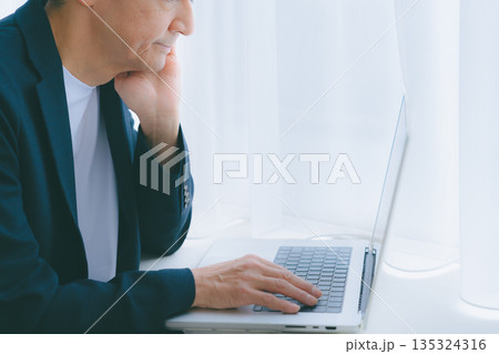窓際でパソコン作業をする男性 135324316