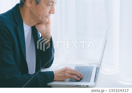 窓際でパソコン作業をする男性 窓際でパソコン作業をする男性 135324317