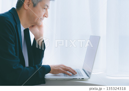 窓際でパソコン作業をする男性 窓際でパソコン作業をする男性 135324318