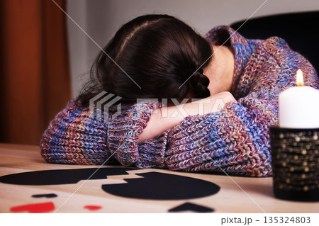 Sad woman lying head down on arms near a broken black heart. Lonely female suffering from a breakup or divorce. Anti-Valentine's Day concept. High quality photo Sad woman lying head down on arms near a broken black heart. Lonely female suffering from a breakup or divorce. Anti-Valentine's Day concept. High quality photo 135324803
