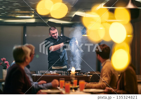 Professional Restaurant Chef Cooking Meat with Flambe Technique at Table for Guests 135324821