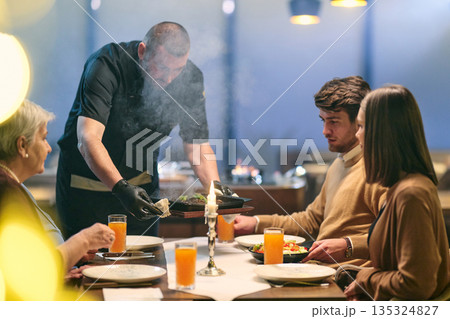 Professional Restaurant Chef Cooking Meat with Flambe Technique at Table for Guests 135324827