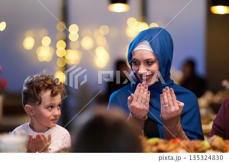 Muslim Mother and Son Praying Before Iftar Meal at Home or Restaurant - Religious Traditions, Ramadan Kareem, and Family Bonding Concept. Muslim Mother and Son Praying Before Iftar Meal at Home or Restaurant - Religious Traditions, Ramadan Kareem, and Family Bonding Concept. 135324830