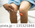 Asian doctor physiotherapist examining, massaging and treatment knee and leg of senior patient in orthopedist medical clinic nurse hospital. 135325848