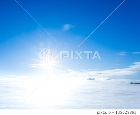 青空と真冬の北海道美瑛町の雪原に沈もうとしている太陽 135325863