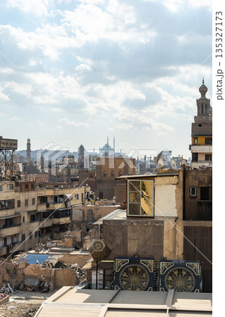 A panoramic view of Old Cairo in Egypt showcases historic buildings, minarets, and rooftops under a cloudy sky. The scene reflects the rich architectural heritage of the city. A panoramic view of Old Cairo in Egypt showcases historic buildings, minarets, and rooftops under a cloudy sky. The scene reflects the rich architectural heritage of the city. 135327173