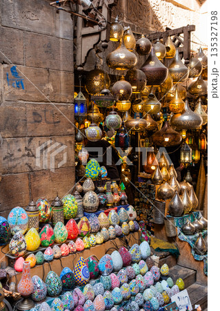 Khan el-Khalili market in Cairo features vibrant stalls filled with colorful goods. Diverse people browse the market, surrounded by traditional architecture and lively atmosphere. Khan el-Khalili market in Cairo features vibrant stalls filled with colorful goods. Diverse people browse the market, surrounded by traditional architecture and lively atmosphere. 135327198