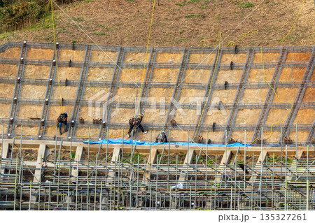 安全のためロープに固定して法面保護作業をする作業員 135327261