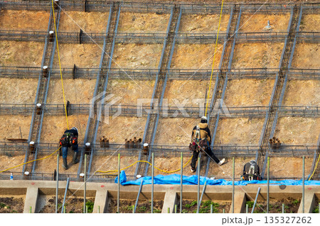安全のためロープに固定して法面保護作業をする作業員 135327262