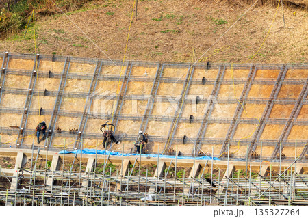 安全のためロープに固定して法面保護作業をする作業員 135327264