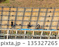 安全のためロープに固定して法面保護作業をする作業員 135327265