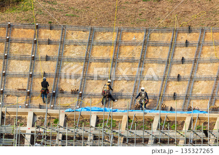 安全のためロープに固定して法面保護作業をする作業員 135327265