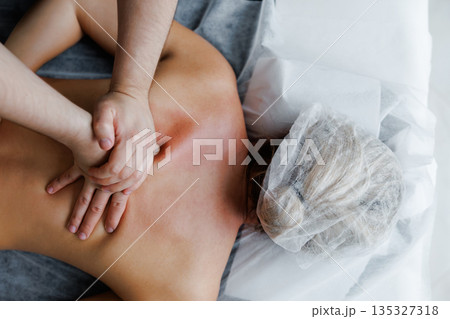 Therapist performing deep tissue back massage on woman 135327318