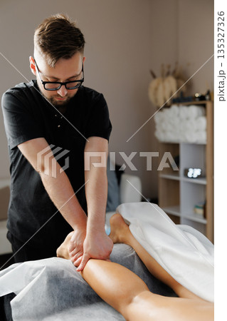 Physiotherapist performing leg massage for muscle recovery Physiotherapist performing leg massage for muscle recovery 135327326