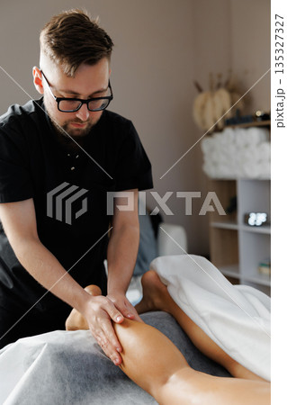 Physiotherapist performing leg massage for muscle recovery 135327327