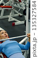 Gym workout. Bench press. Caucasian woman trains her pectoral muscles in the gym. Caucasian woman trains chest muscles using bench press during gym workout. 135327584