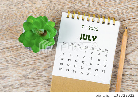 July 2026 monthly desk calendar and pencil with plant pot decoration. 135328922