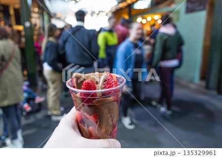 Hand Holding Fresh Strawberries with Melted Chocolate in Market 135329961