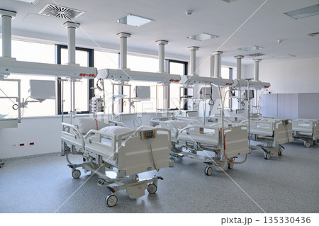 Modern hospital ward with multiple beds and advanced medical equipment in bright, clean environment Modern hospital ward with multiple beds and advanced medical equipment in bright, clean environment 135330436