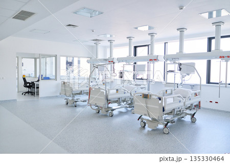 Modern hospital room with multiple empty beds and bright windows in a healthcare setting Modern hospital room with multiple empty beds and bright windows in a healthcare setting 135330464