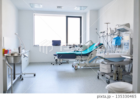 Clean and sterile hospital room with medical equipment and patient beds for healthcare services Clean and sterile hospital room with medical equipment and patient beds for healthcare services 135330465