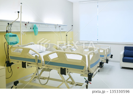 Hospital room with empty beds and medical equipment in a bright, clean environment 135330596