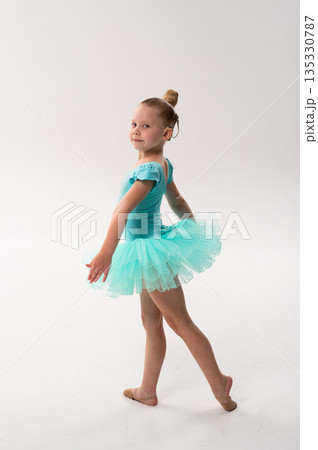 Young dancer with a cochlear implant smiles while posing in a turquoise ballet tutu. Inclusive performance, hearing technology, and creative childhood development through classical dance. 135330787