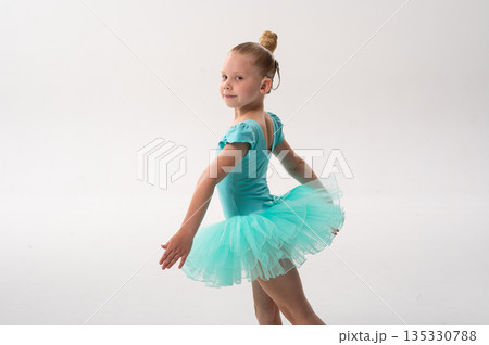 Young ballerina with a cochlear implant turns in a turquoise tutu in the studio. Inclusive ballet, auditory technology, and joyful childhood expression through dance and movement. 135330788