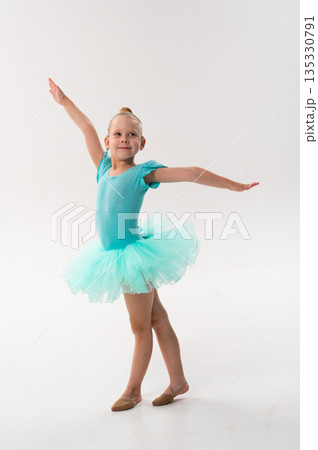 A smiling ballerina with a cochlear implant poses in a turquoise tutu on stage. Inclusive ballet, hearing support, and self expression through classical dance and childhood performance. 135330791