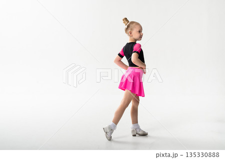 Ballroom dancer with cochlear implant turning in pink skirt in studio. Copy space. Pediatric hearing rehabilitation, physical coordination and inclusive childhood performance through dance training 135330888
