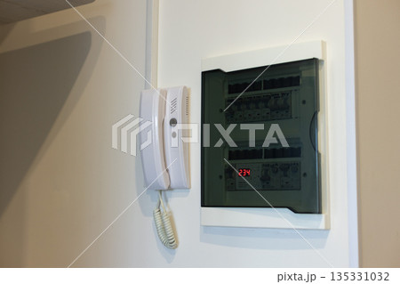 Intercom with electrical panel in the apartment on a white wall close-up Intercom with electrical panel in the apartment on a white wall close-up 135331032