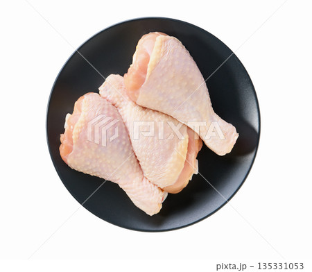 raw chicken legs or chicken drumsticks on a black plate isolated on a white background, top view. raw chicken legs or chicken drumsticks on a black plate isolated on a white background, top view. 135331053