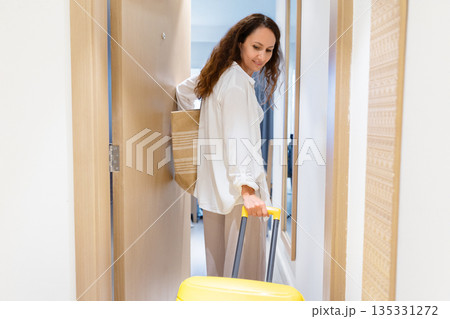Adult caucasian woman entering hotel room with yellow suitcase, first arrival moment 135331272