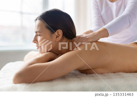 Relaxed woman enjoying spa body massage, smiling gently and feeling refreshed 135331463