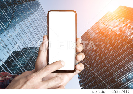 Smartphone Mockup in Hands Against Modern City Skyscrapers Smartphone Mockup in Hands Against Modern City Skyscrapers 135332437