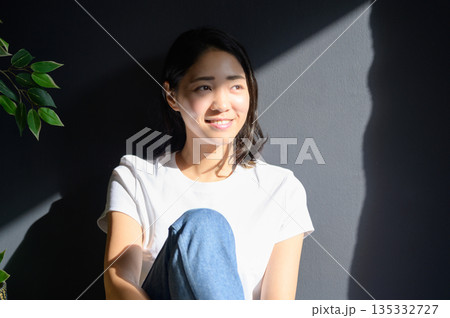 グレー背景で日差しを浴びる女性 グレー背景で日差しを浴びる女性 135332727
