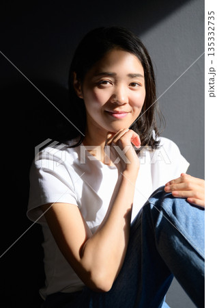 グレー背景で日差しを浴びる女性 グレー背景で日差しを浴びる女性 135332735