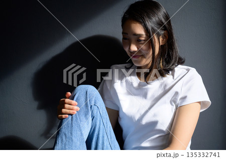 グレー背景で日差しを浴びる女性 グレー背景で日差しを浴びる女性 135332741
